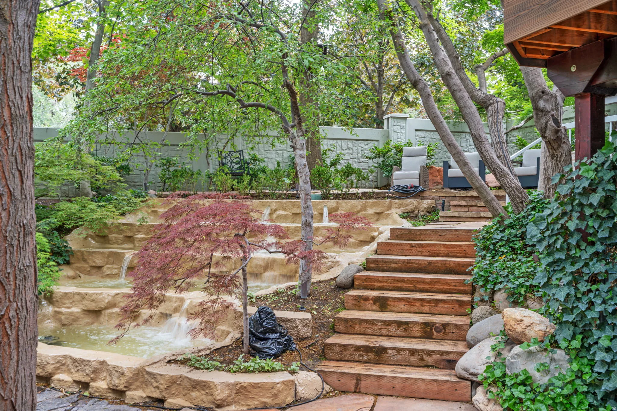 Tiered water feature with a Japanese maple, complemented by natural stone landscaping