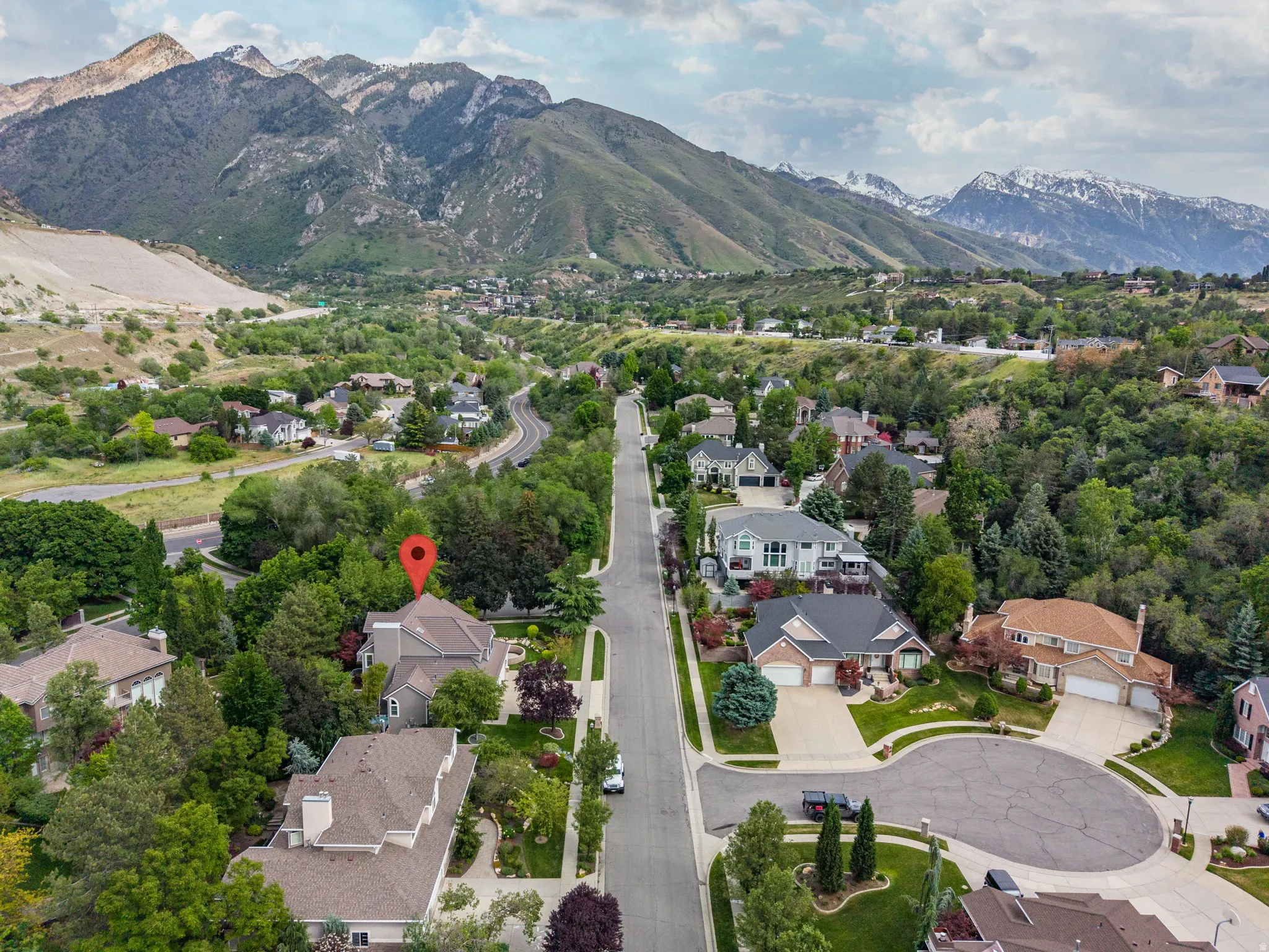 Residential property nestled in a verdant landscape, surrounded by mature trees and mountain ranges
