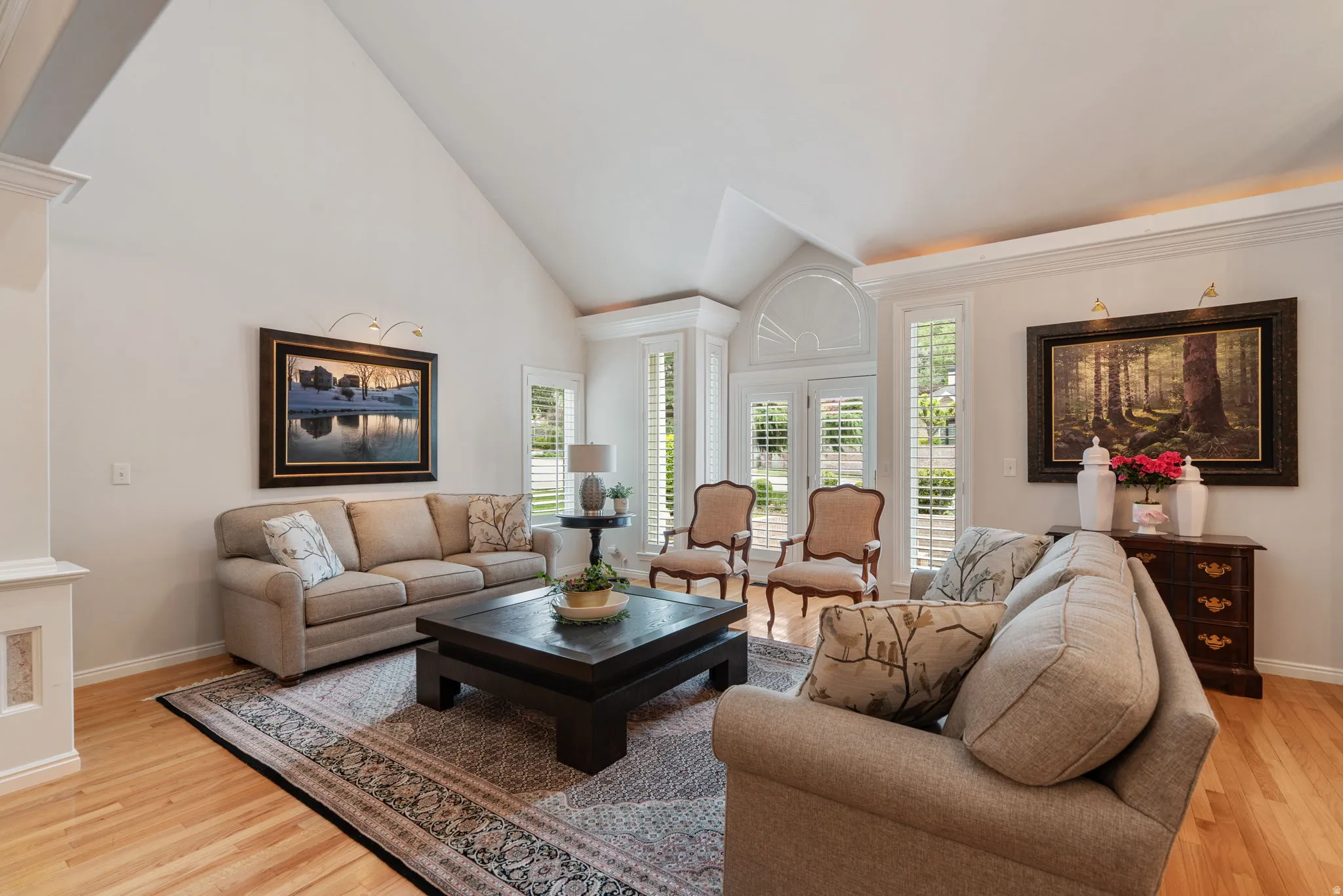 Living space featuring vaulted ceilings, wood-finish flooring,  and white plantation shutters