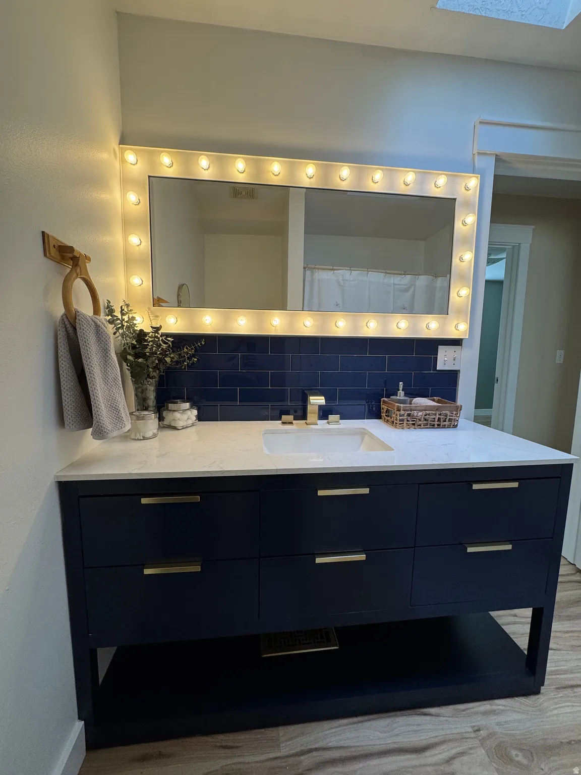 Vanity with a white countertop and integrated sink, gold-finish faucet, and blue subway tile backsplash
