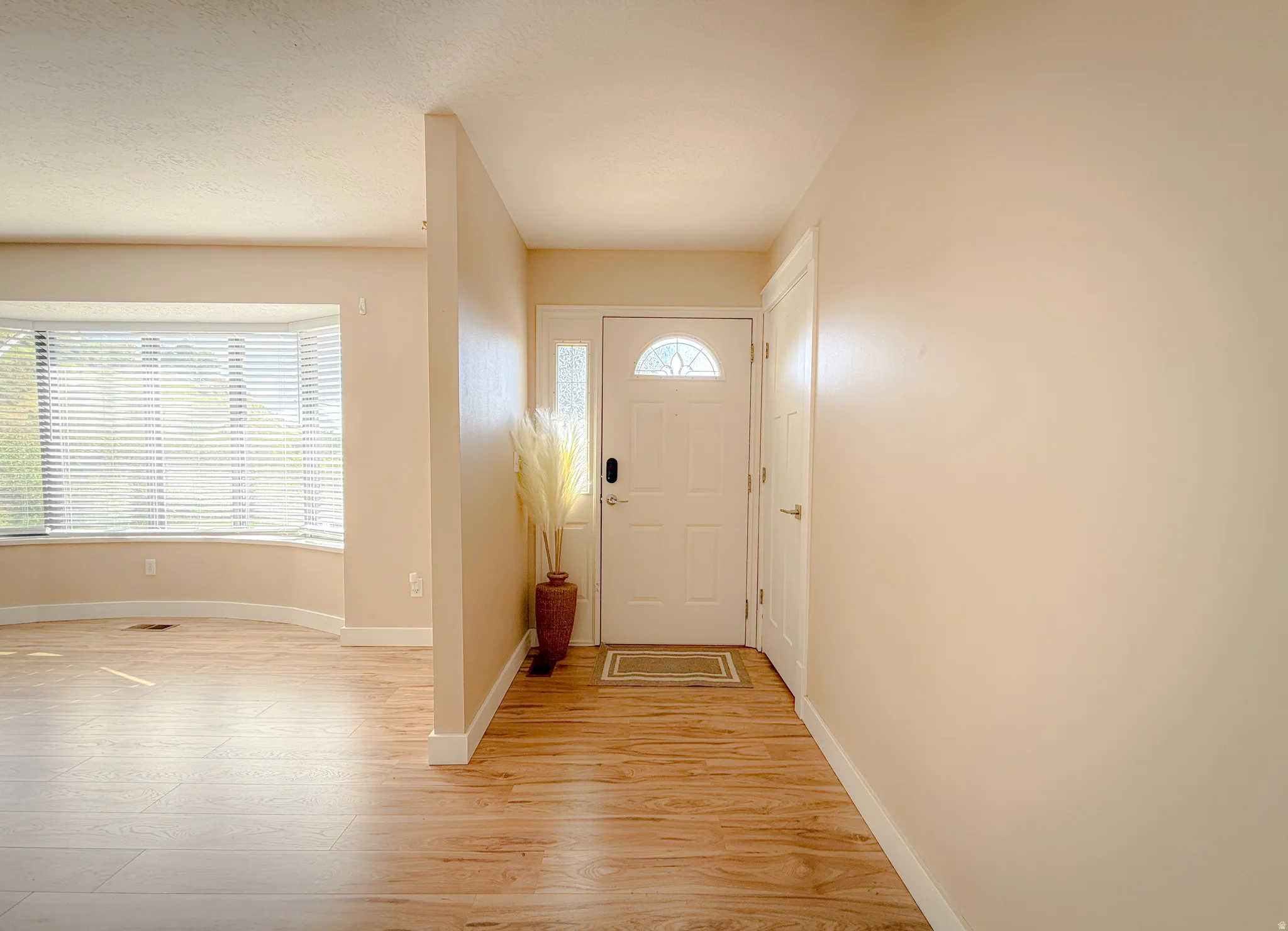 Entryway featuring wood-finish flooring, a white front door with an arched window, and a sidelight