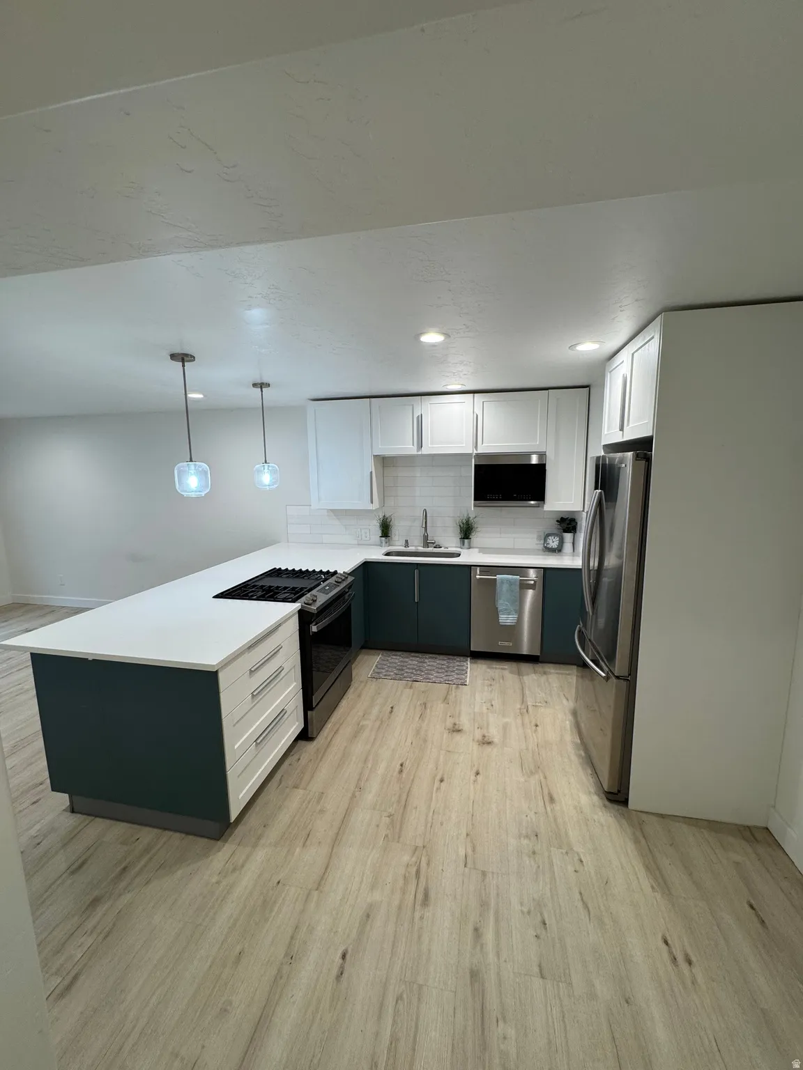 Kitchen featuring a large island with white countertop, integrated gas range, and pendant lighting