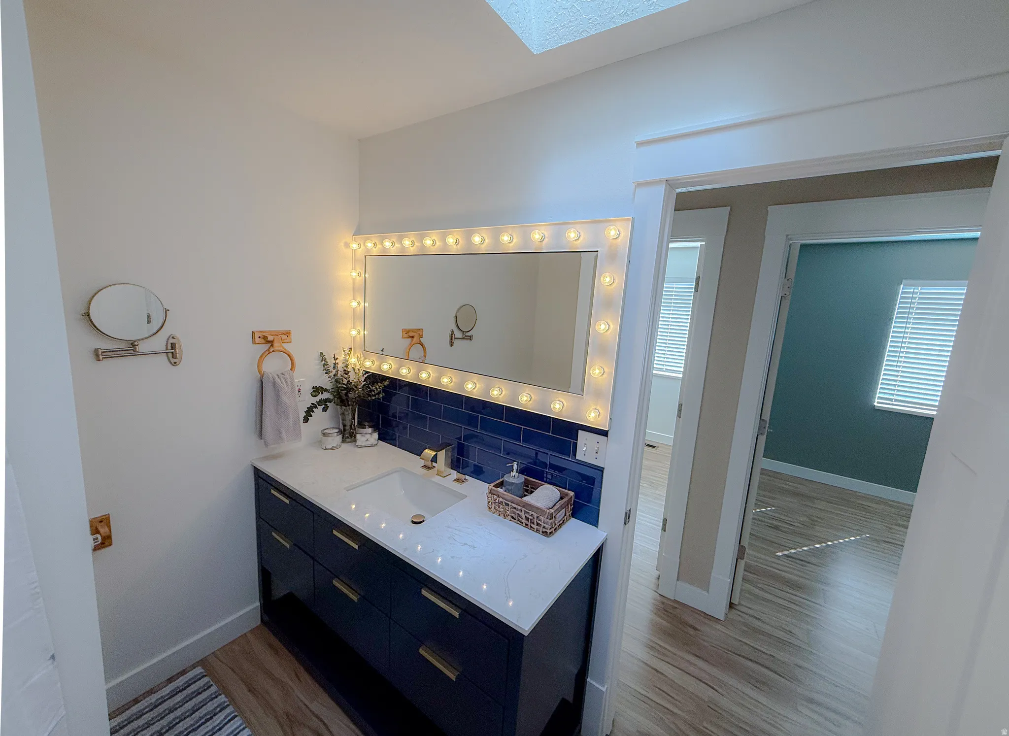 Bathroom featuring a navy blue vanity with gold hardware, white countertop, and a white integrated sink