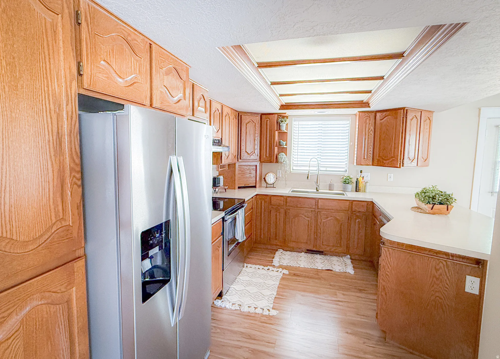 Kitchen featuring wood-finish cabinetry, light countertops, wood-finish flooring, and a stainless steel side-by-side refrigerator