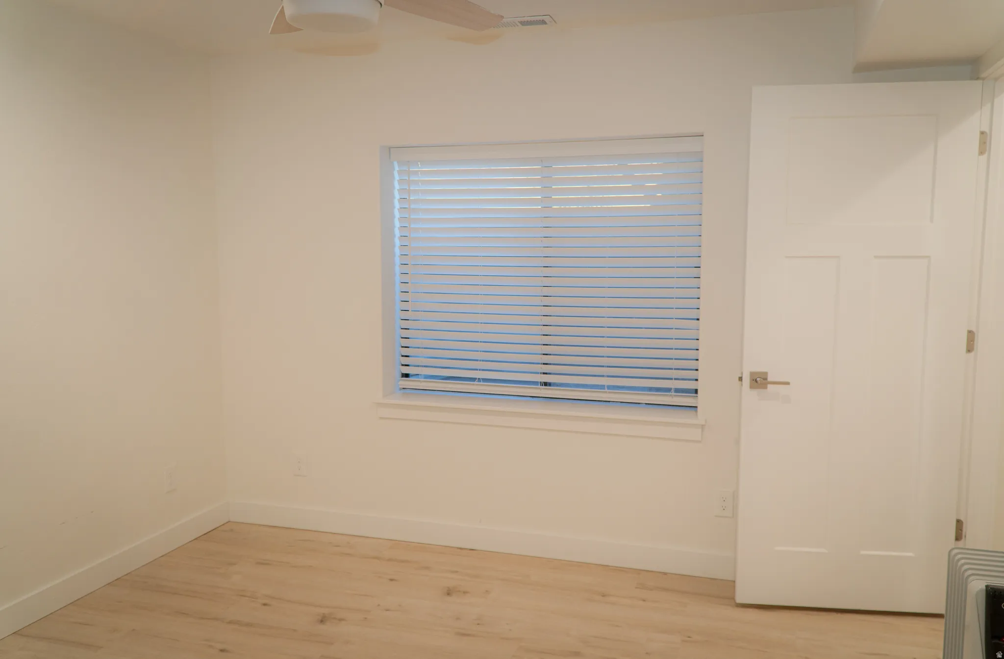 Room featuring light wood-finish flooring, white baseboards, and neutral wall paint