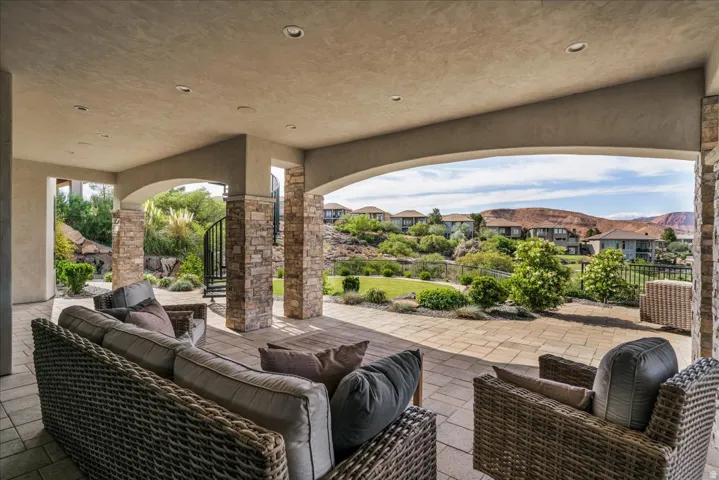 Expansive covered patio featuring stone-clad columns, arched openings, recessed lighting, and a paved surface