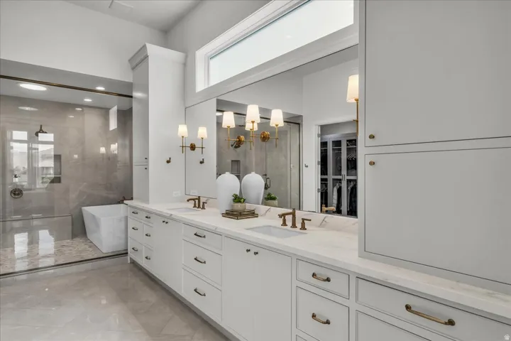 Expansive primary bathroom featuring a double vanity with white cabinetry and light-toned countertops