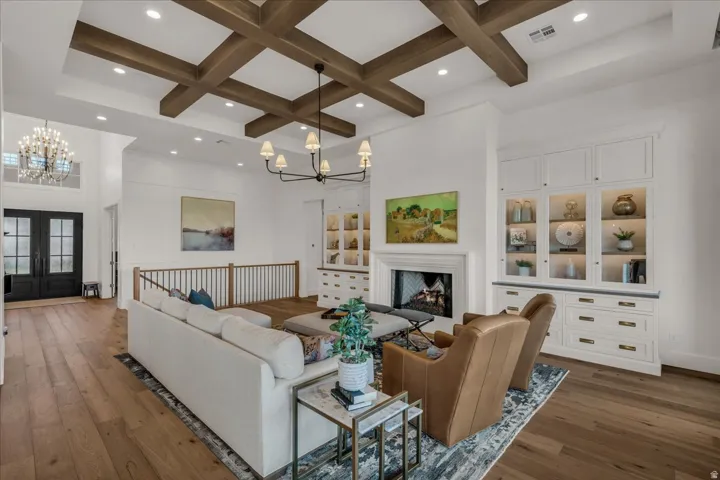 Living space featuring wood-finish flooring, a coffered ceiling with recessed lighting, and a chandelier