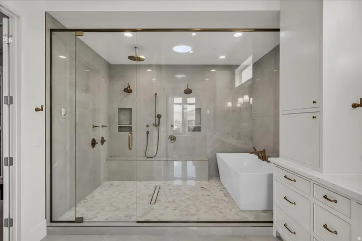 Primary bathroom: walk-in shower with full glass enclosure, dual shower heads, and built-in bench