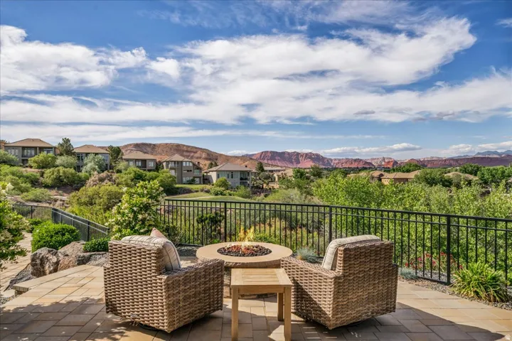 Expansive outdoor patio featuring a paver stone surface, a built-in fire pit, and a black metal railing
