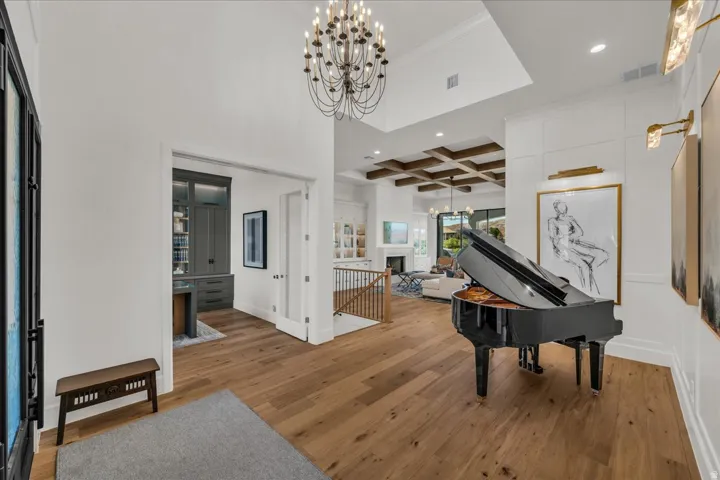 Grand entryway featuring wood-finish flooring, a contemporary chandelier, and wainscoting detailing