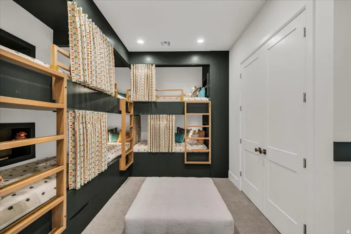 Built-in bunk beds with individual privacy curtains, recessed lighting, and a soft carpeted floor
