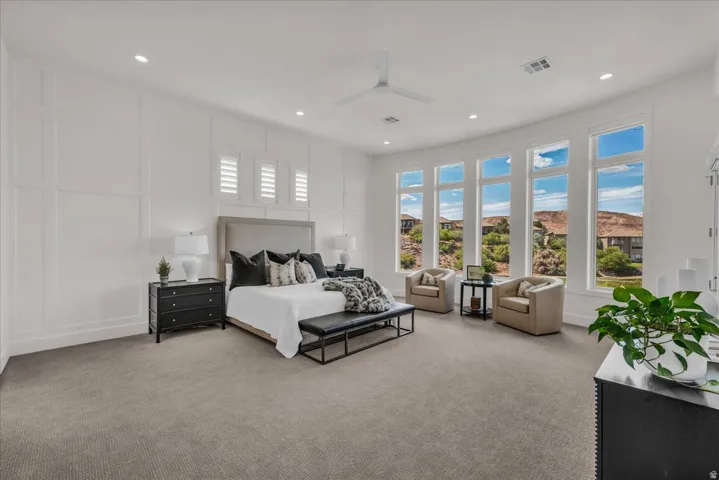 Primary bedroom featuring five tall windows with white framing, recessed lighting, and a white ceiling fan
