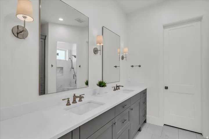 Dual vanity with gray cabinetry, white countertops, and brushed nickel fixtures