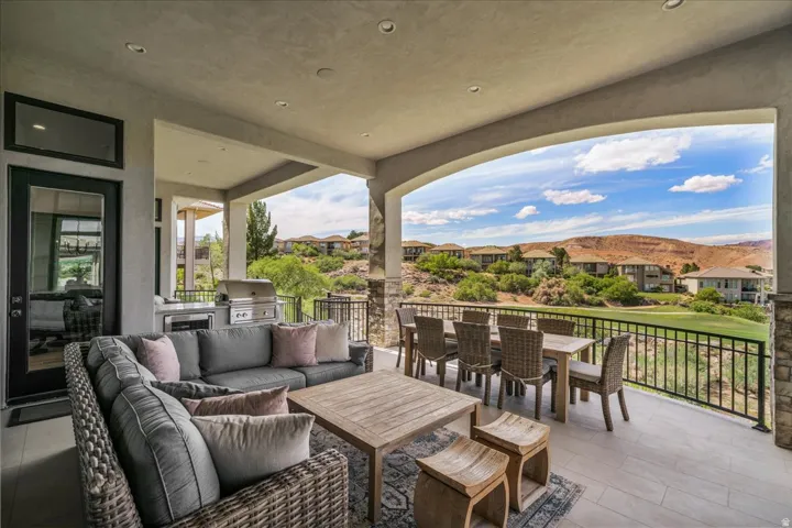 Expansive covered patio featuring a built-in outdoor kitchen with stainless steel appliances, recessed lighting, and tile flooring