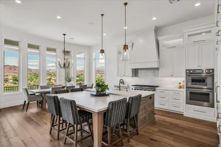 Gourmet kitchen featuring a large central island, white shaker cabinetry, stainless steel appliances, and wood-finish flooring