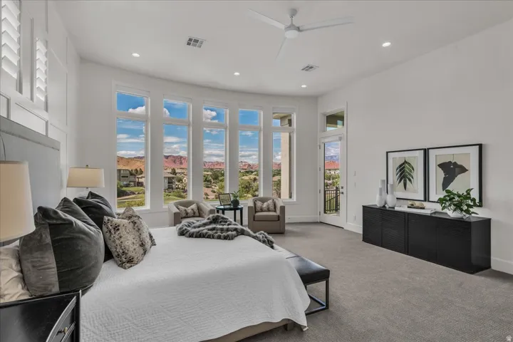Primary bedroom with full-height windows with a curved design, white shaker shutters, a private balcony, recessed lighting, and a ceiling fan