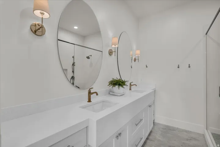 Double vanity featuring white shaker cabinetry, white countertops, and dual oval mirrors