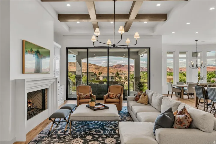 Spacious great room featuring a coffered ceiling with wood beams, a fireplace with a herringbone-patterned firebox, and large glass sliding doors