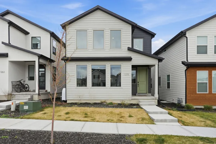 Contemporary two-story residence featuring light-colored siding with dark trim accents