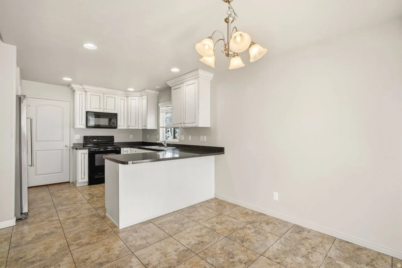 Kitchen featuring white cabinetry with crown molding, dark countertops, black range, and built-in microwave