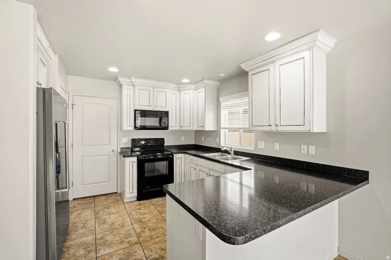 Kitchen featuring white cabinetry, dark speckled countertops, and stainless steel appliances