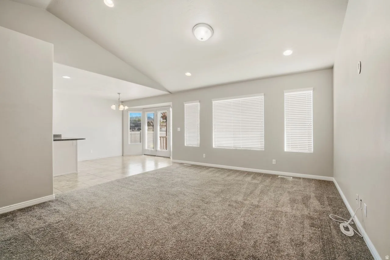 Spacious living area featuring vaulted ceilings, recessed lighting, and soft gray carpeting