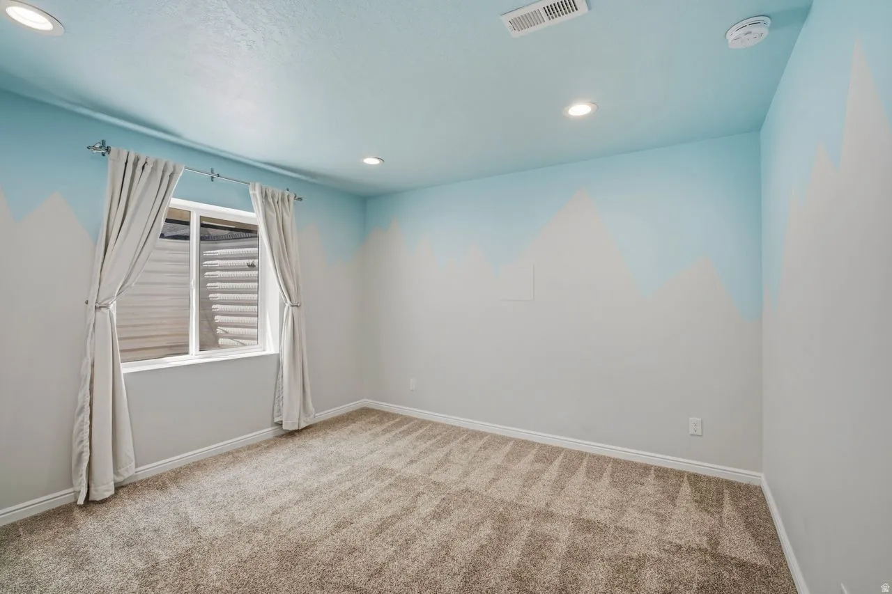 Carpeted room featuring a single window with curtains, recessed lighting, and light blue and white wall painting