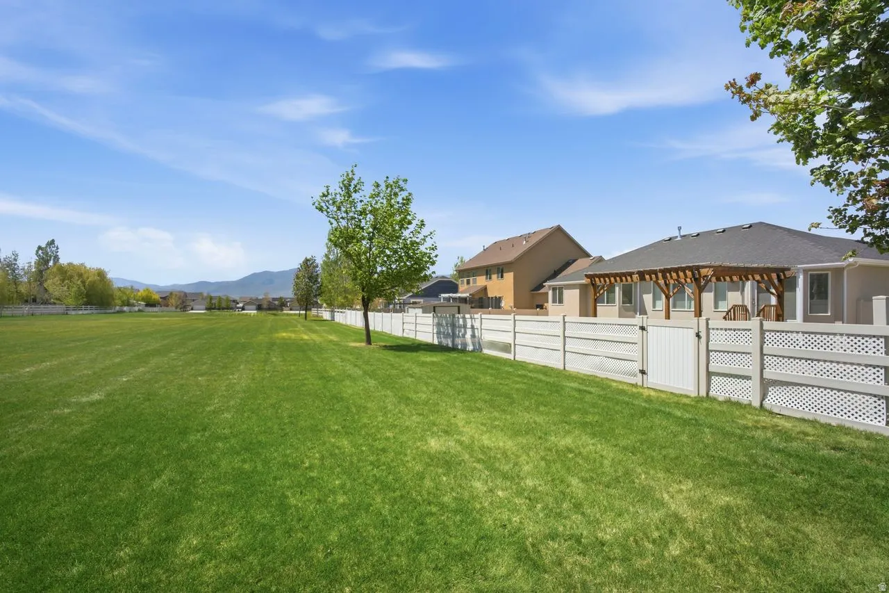Expansive green lawn with a white fence defining the property boundary