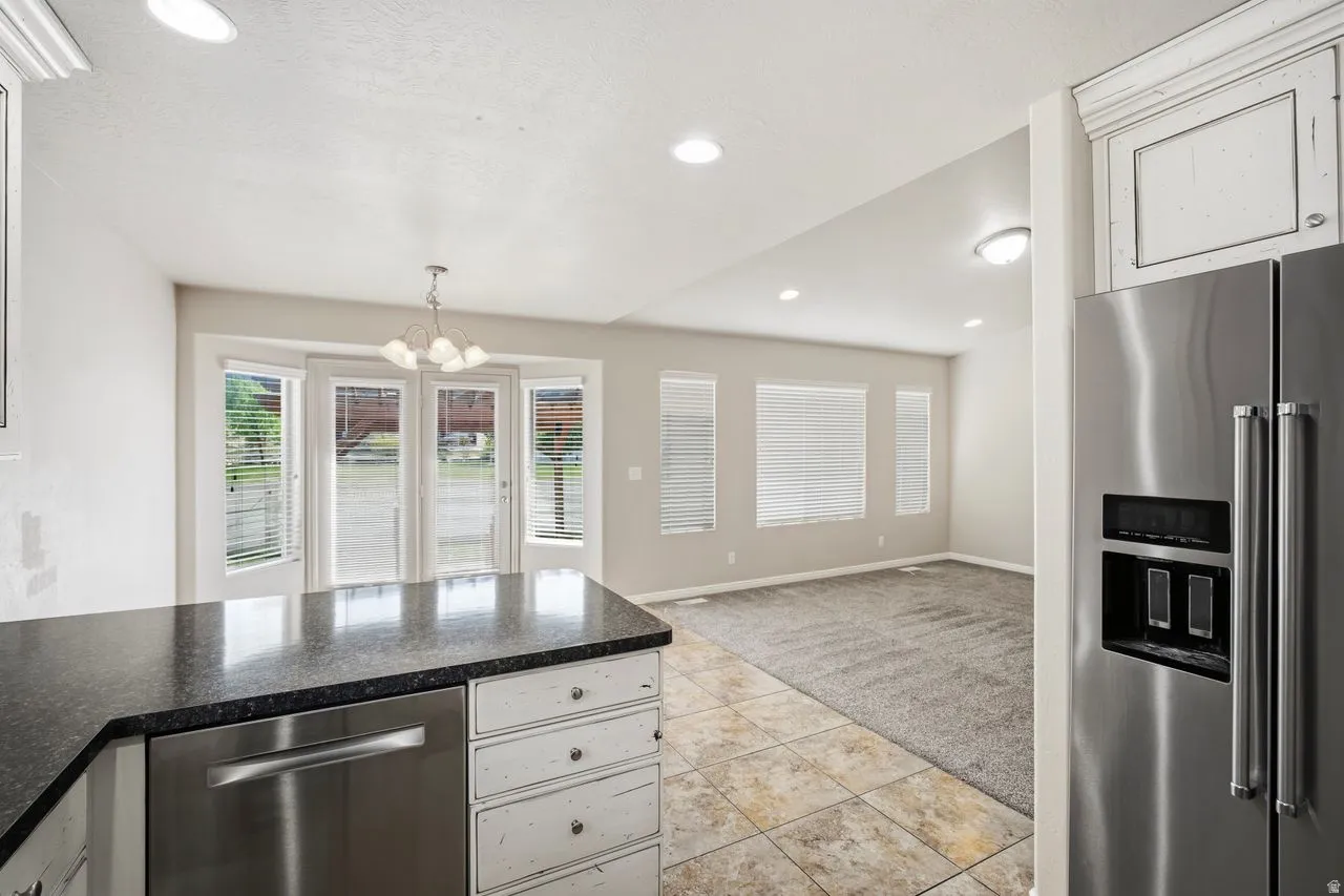 Kitchen area featuring a dark countertop, white cabinetry with decorative hardware, and a stainless steel dishwasher