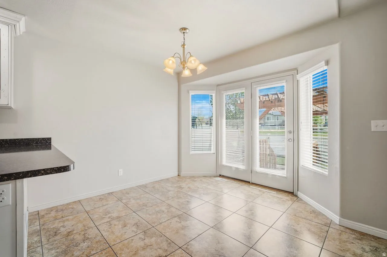 Bay window area featuring white double French doors and flanking windows with blinds, recessed chandelier lighting, and a tile floor