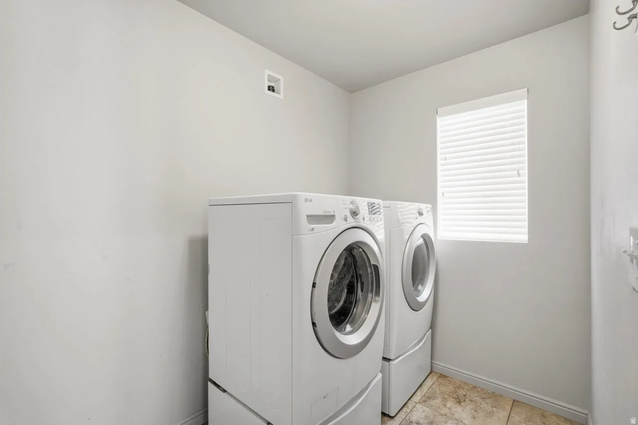Dedicated laundry area featuring tile flooring and a window with horizontal blinds