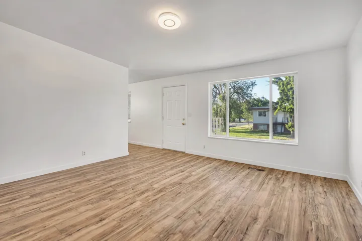 Spacious room featuring wood-finish flooring, white walls, and a large picture window
