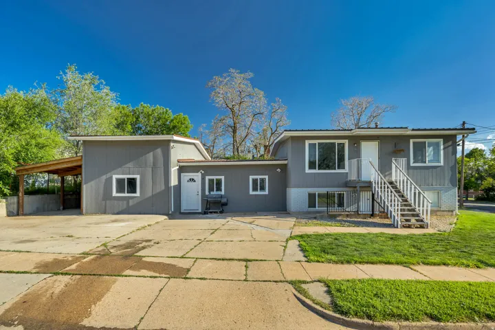 Exterior featuring gray siding, a covered carport, multiple windows, and an external staircase