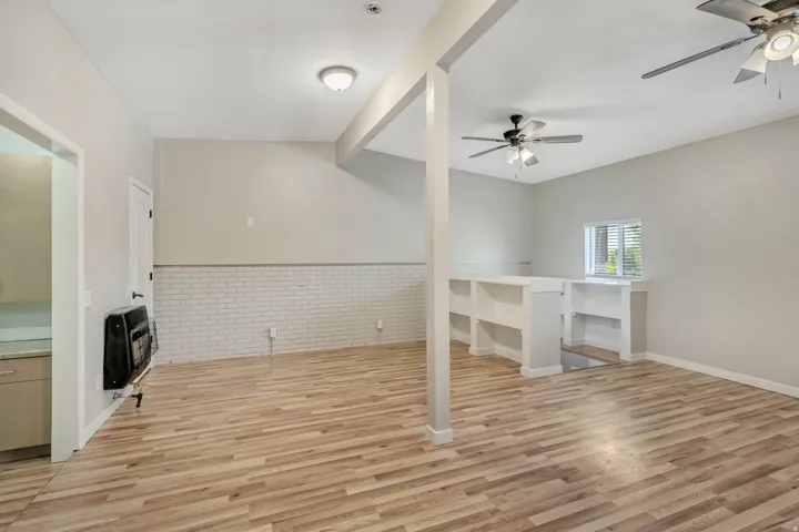 Spacious open area featuring wood-finish flooring, white brick wainscoting, and recessed lighting