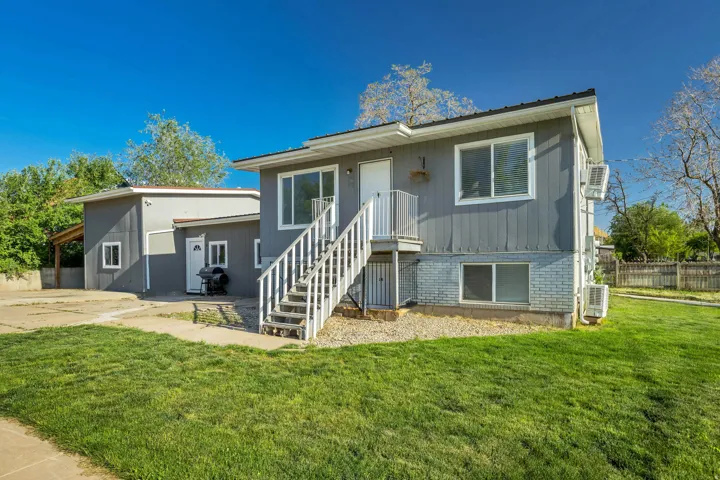 Exterior featuring gray vertical siding, white trim, and a prominent white staircase