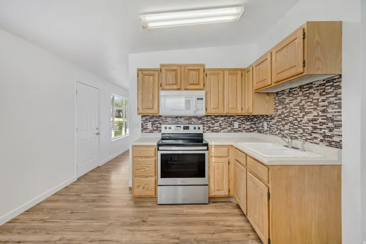 Kitchen featuring wood-finish cabinetry, light countertops, and a mosaic tile backsplash