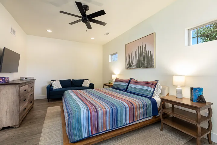 Primary bedroom with high ceilings, recessed lighting, wood-finish flooring, and multiple windows