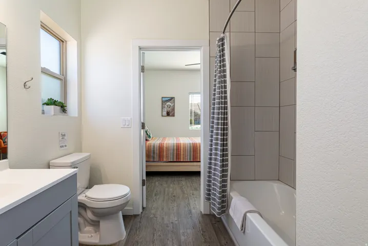 Full bathroom featuring a white vanity with integrated sink, toilet, and a tub/shower combination with light gray wall tile