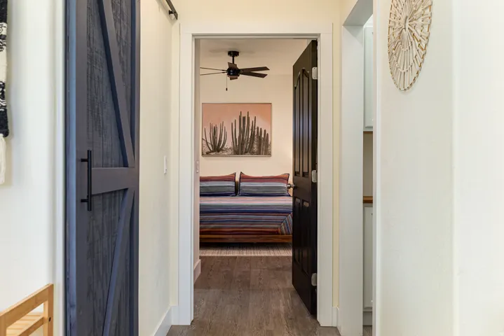 Hallway featuring a dark wood-finish barn door, light-colored walls, wood-finish flooring, and a dark paneled interior door