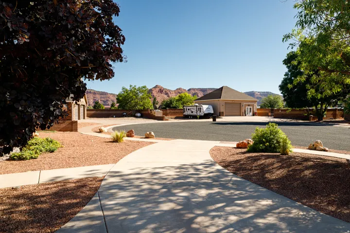 Paved driveway with a curved walkway, xeriscape landscaping, and a two-car garage structure with a hip roof