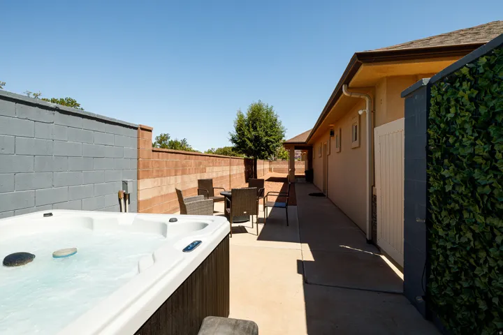 Backyard featuring a built-in hot tub, concrete patio, and privacy walls