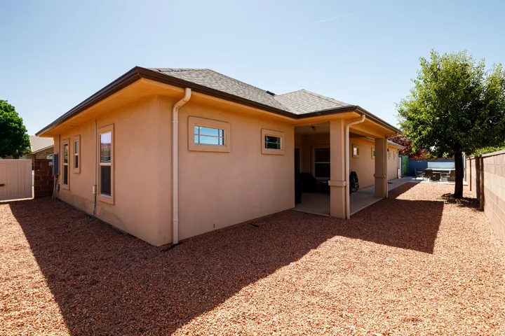 Exterior features a stucco finish, covered patio, and a gravel-covered yard