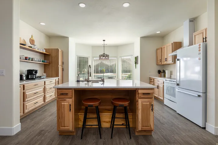 Kitchen with a central island featuring a sink, light-toned countertops, and wood-finish cabinetry