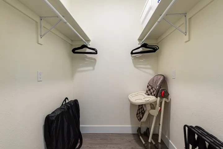 Spacious closet featuring dual shelving and clothing rods, light-toned walls, and wood-finish flooring