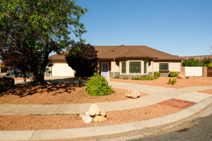 Single-story residence featuring a tan stucco exterior with a brown shingle roof