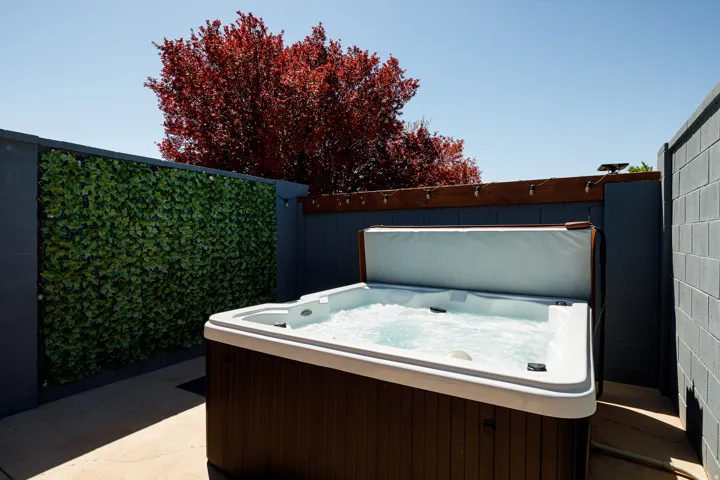 Outdoor spa with bubbling water, set against a privacy wall featuring artificial foliage