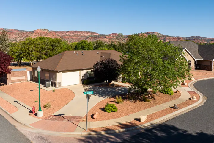 Corner lot residence featuring a two-car garage, concrete driveway, and low-maintenance xeriscaping