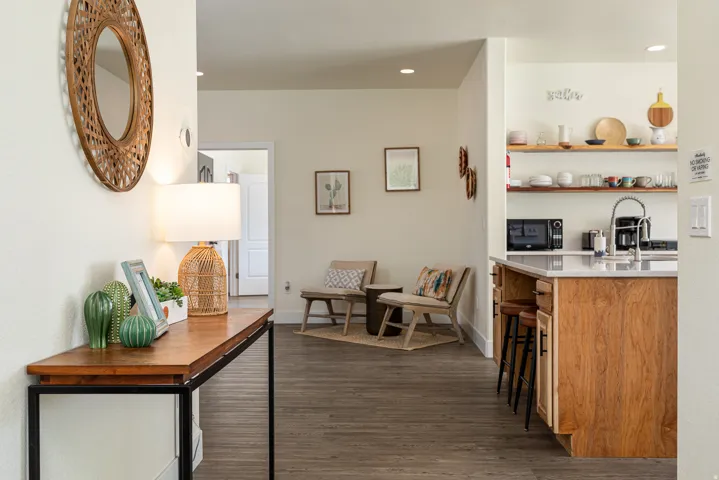 Kitchen island with wood-finish cabinetry and a light-toned countertop, featuring a gooseneck faucet