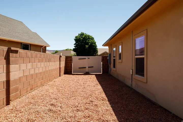 Side yard with a gravel ground cover, block perimeter wall, and a privacy gate